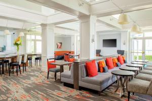 アービングにあるHomewood Suites by Hilton Dallas-Irving-Las Colinasのテーブル、椅子、オレンジの枕が備わる広い客室です。