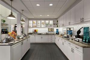 a large kitchen with white cabinets and wooden floors at Homewood Suites by Hilton Dallas-Plano in Plano