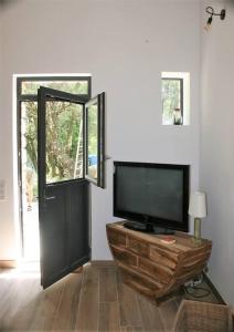 a living room with a flat screen tv and a door at Gîte cévenol pleine nature tout confort in Soudorgues