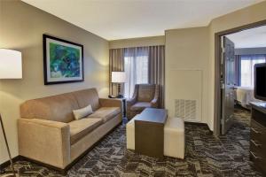 - un salon avec un canapé et une chaise dans une chambre d'hôtel dans l'établissement Homewood Suites by Hilton Dayton South, à Miamisburg