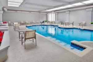 una piscina con agua azul en una habitación con mesas y sillas en Embassy Suites Dallas - Park Central Area, en Dallas