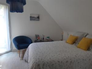 una camera da letto con un letto con cuscini gialli e una sedia blu di Chambre d'hôte cosy & zen a Saint-Jean-la-Poterie