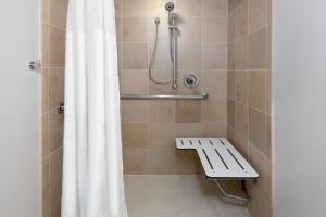 una doccia con tenda e panca in bagno di Embassy Suites Dallas - Park Central Area a Dallas