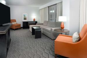 sala de estar con sofá y TV en Embassy Suites Dallas - Park Central Area, en Dallas