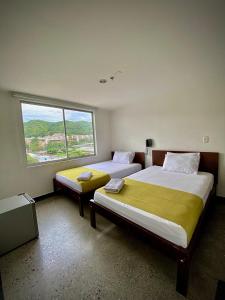 two beds in a room with a large window at HOTEL RIVERA CENTRAL in Bucaramanga