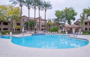 een groot zwembad met palmbomen op de achtergrond bij Elegant Scottsdale Condo - Newly Refurbished Ground Floor Unit in Scottsdale