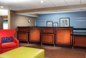 a waiting room with a red chair and a desk at Hampton Inn Denver - Northwest Westminster in Westminster