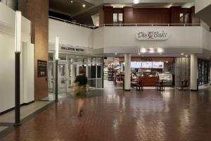 a woman walking through a shopping mall with a store at Hilton Arlington in Arlington