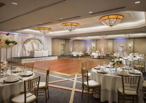 um salão de banquetes com mesas e cadeiras brancas e uma pista de dança em Hilton Arlington em Arlington