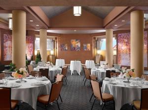 una sala de banquetes con mesas y sillas y ropa de cama blanca en Hilton Arlington, en Arlington