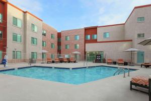 a pool in front of a building with tables and chairs at Hampton Inn & Suites Denver Tech Center in Centennial