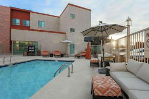 a pool at a hotel with a couch and an umbrella at Hampton Inn & Suites Denver Tech Center in Centennial