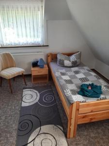 um pequeno quarto com uma cama e uma cadeira em Ferienhaus Rosemarie Erlbach Vogtland em Erlbach