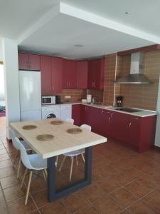cocina con mesa de madera y armarios rojos en Apartamento LA CORREDERA, en Arenas de San Pedro