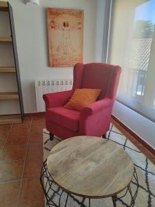Sala de estar con silla roja y mesa de centro en Apartamento LA CORREDERA, en Arenas de San Pedro