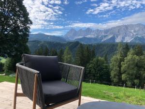 a wicker chair sitting on a patio with a view of mountains at Selbstversorgerhaus Herisch in Schladming