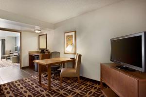 a hotel room with a desk and a flat screen tv at Embassy Suites Dallas - DFW International Airport South in Irving