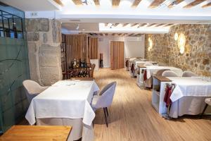 a row of tables in a restaurant with white linens at Hotel El Doncel in Sigüenza