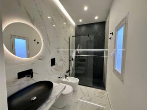 La salle de bains est pourvue de toilettes, d'un lavabo et d'un miroir. dans l'établissement Alma Rooms, à Lampedusa