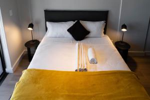a bed with two pillows and a yellow blanket on it at THE TOKYO in Cape Town