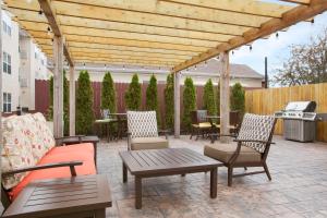 eine Terrasse mit einer hölzernen Pergola mit Stühlen und Tischen in der Unterkunft Homewood Suites Grand Rapids in Grand Rapids