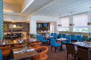 un ristorante con tavoli in legno e sedie blu di Hilton Garden Inn Edison/Raritan Center a Edison