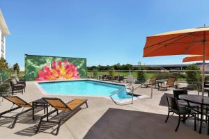 un patio con piscina, mesas y sillas en Homewood Suites by Hilton Houston NW at Beltway 8 en Houston