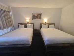 2 Betten in einem kleinen Zimmer mit 2 Lampen in der Unterkunft The Marlborough Hotel in Winnipeg