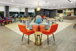 a cafeteria with a couch and tables and chairs at Home2 Suites By Hilton Sugar Land Rosenberg in Sugar Land