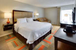 a hotel room with a large bed and a chair at Hampton Inn Harrisonburg - University in Harrisonburg