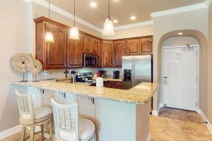 a kitchen with wooden cabinets and a counter with chairs at Sans Souci 303 in Pensacola Beach