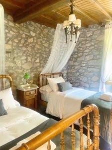 a bedroom with two beds and a stone wall at Casa do Viñal 