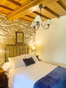 1 dormitorio con cama blanca y pared de piedra en Casa do Viñal 