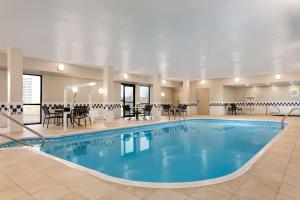 a pool in a hotel with tables and chairs at Hampton Inn Wichita-East in Wichita