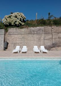 a group of white lounge chairs next to a swimming pool at El Chisco in San Cosme