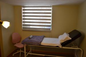 uma cama e uma cadeira num quarto com uma janela em La Casona Recoleta em Arequipa