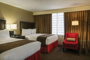 Cette chambre d'hôtel comprend deux lits et un fauteuil rouge. dans l'établissement Doubletree by Hilton Los Angeles Downtown, à Los Angeles