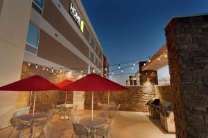 a patio with tables and umbrellas in front of a building at Home2 Suites by Hilton Midland in Midland