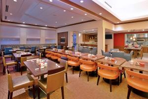 Hilton Garden Inn Chicago/Midway Airport في شيكاغو: مطعم فيه طاولات وكراسي في الغرفة