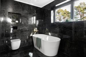 ein schwarzes Bad mit einer Badewanne und einem WC in der Unterkunft Moderne nydelig villa med Panorama Utsikt in Sandefjord