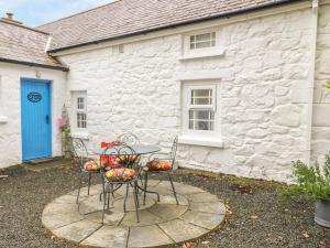 a table and chairs in front of a white building at Rosslare Cottage in Broughshane