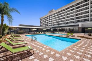 a swimming pool with lounge chairs and a building at DoubleTree by Hilton New Orleans Airport in Kenner