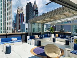 een dakterras met banken en tafels en een skyline van de stad bij Hilton New York Fashion District in New York