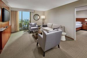Habitación de hotel con sofá, sillas y TV en Hilton Pasadena, en Pasadena