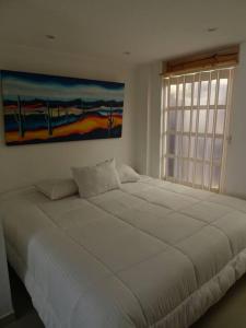 uma grande cama branca num quarto com uma janela em Casa tranquila em Mosquera