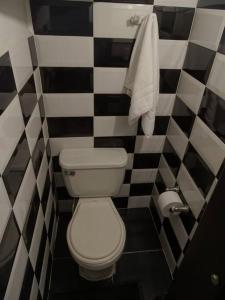 uma casa de banho com um WC branco e azulejos pretos e brancos. em Casa tranquila em Mosquera