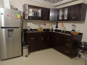 a kitchen with wooden cabinets and a stainless steel refrigerator at Casa tranquila in Mosquera