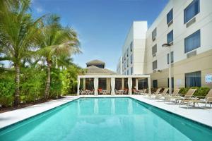 uma piscina em frente a um hotel com palmeiras em Hilton Garden Inn West Palm Beach Airport em West Palm Beach