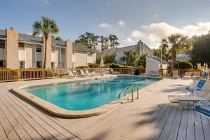 a large swimming pool with chairs and a wooden deck at St Simons Island Condo with Deck and Outdoor Shower in Saint Simon Mills