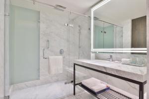uma casa de banho com um lavatório e um chuveiro com um espelho. em Le Méridien Amritsar em Amritsar